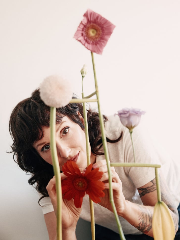 Portrait of Vancouver artist Jennifer Latour arranging colourful flowers for a botanical sculpture, photographed by Pooya Nabei.