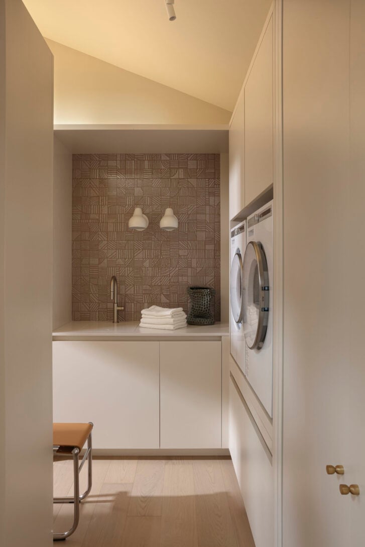 Ergonomic laundry setup with elevated washer-dryer and pull-out shelf in Acropolis House, West Vancouver