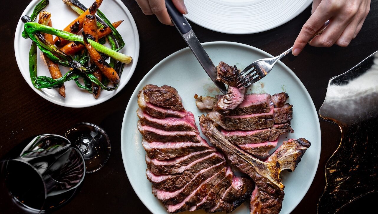 Someone cutting into a steak at Elisa Steakhouse