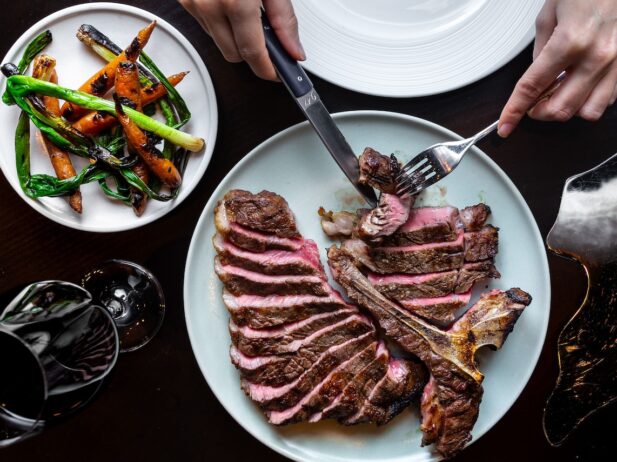 Someone cutting into a steak at Elisa Steakhouse