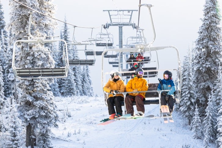 Skiers riding a chairlift through the snowy landscape at Sun Peaks