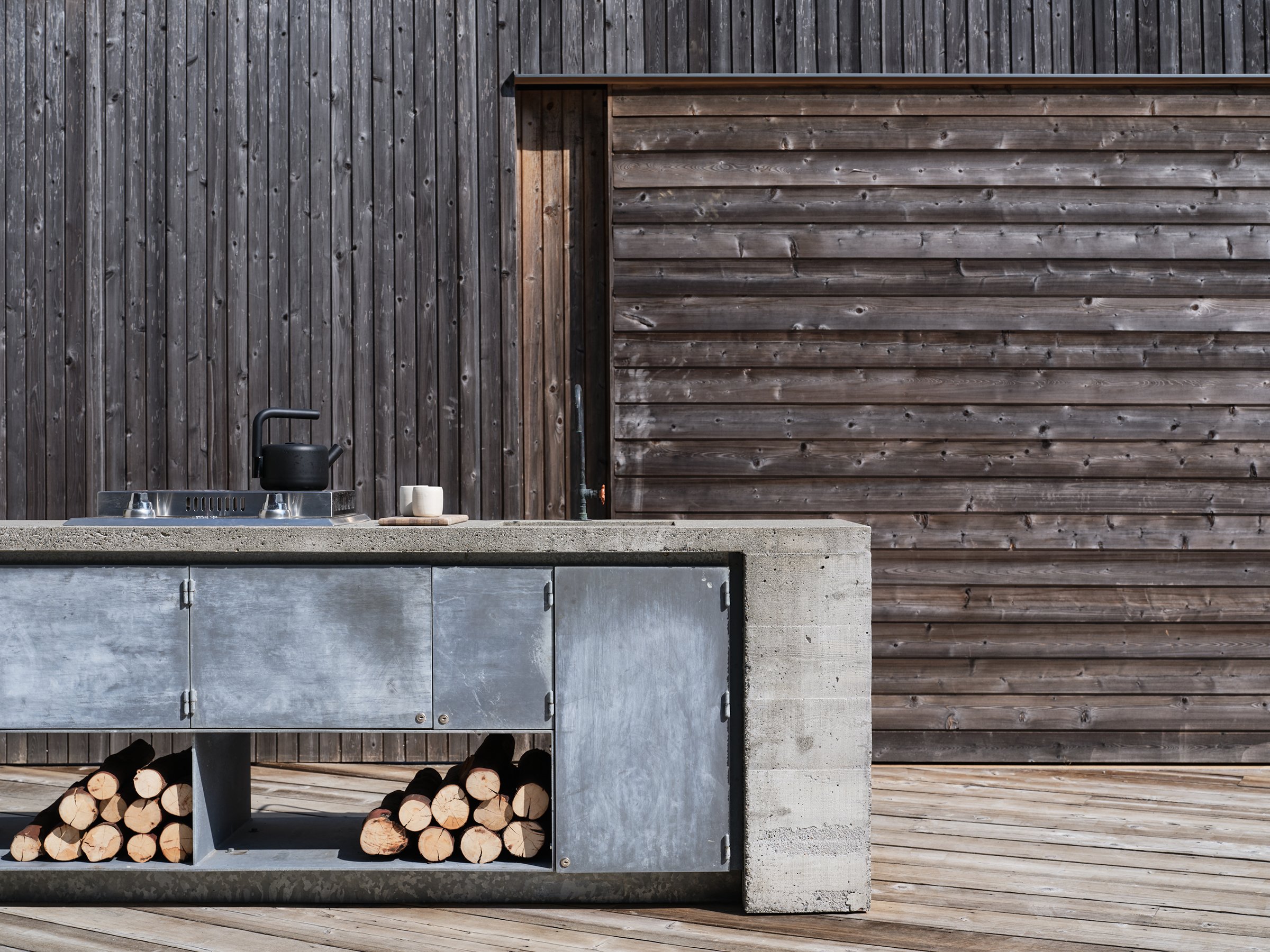 Open-air kitchen and sliding walls connecting shared family wings at Cabin 1+1, Galiano Island