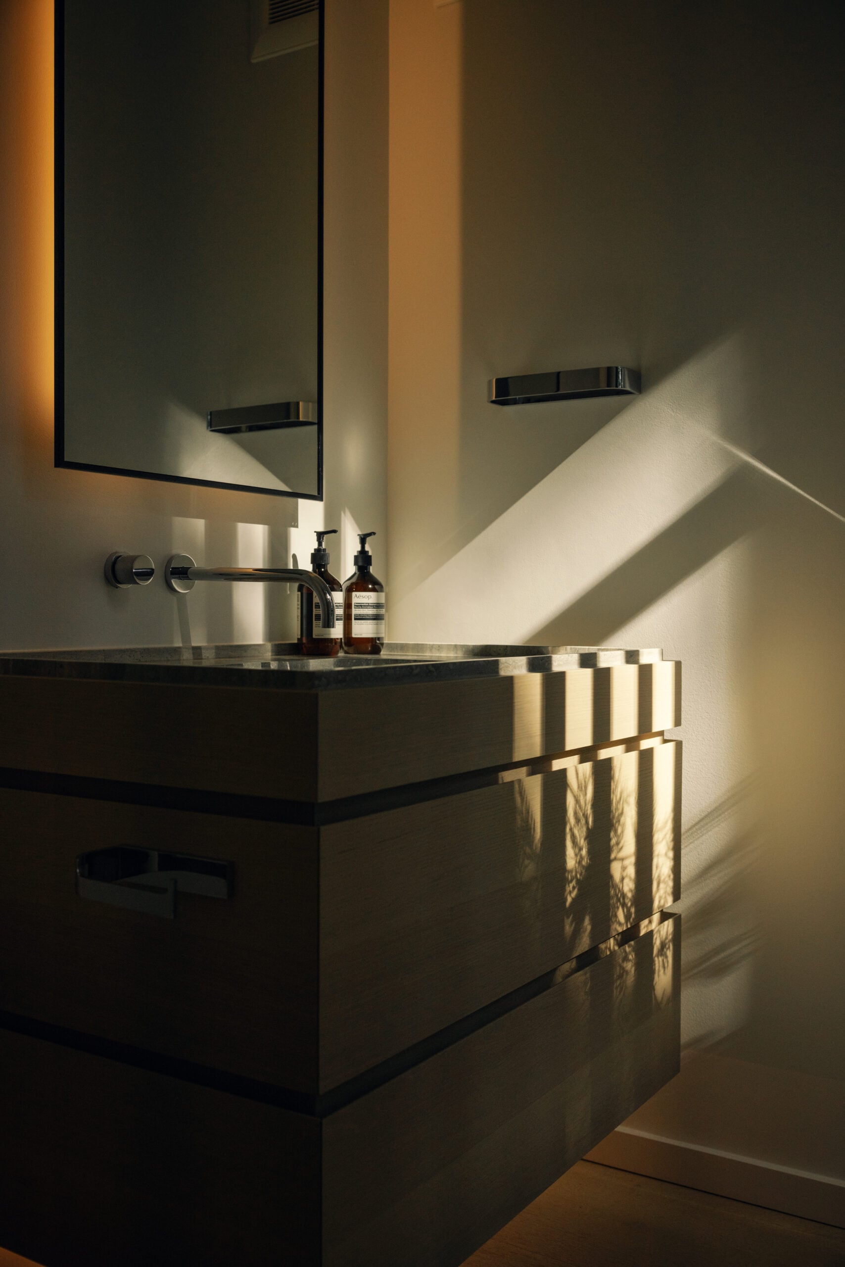 Wood bathroom vanity with a rectangular mirror above the sink