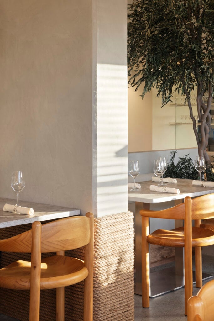 Detail of a rope-wrapped column base beside a dining table with pine chairs