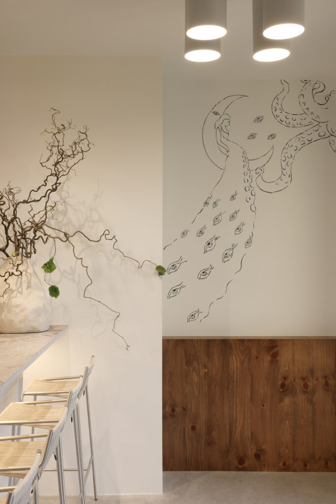 Bar area with bar stools and a mural of moon goddess Selene with flowing tentacles patterned with eyes
