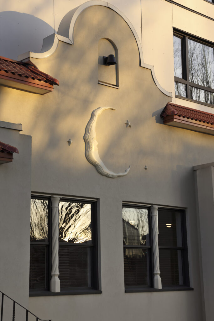 Exterior of the reconstructed heritage façade, featuring a sculpted crescent moon and stars on a Mediterranean-style stucco wall with terracotta roof tiles