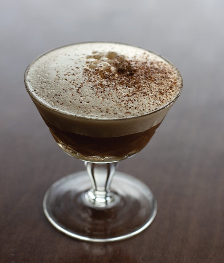 Chez Solange winter mocktail in a coupe glass, topped with foam and grated cinnamon, from St. Lawrence restaurant in Vancouver.