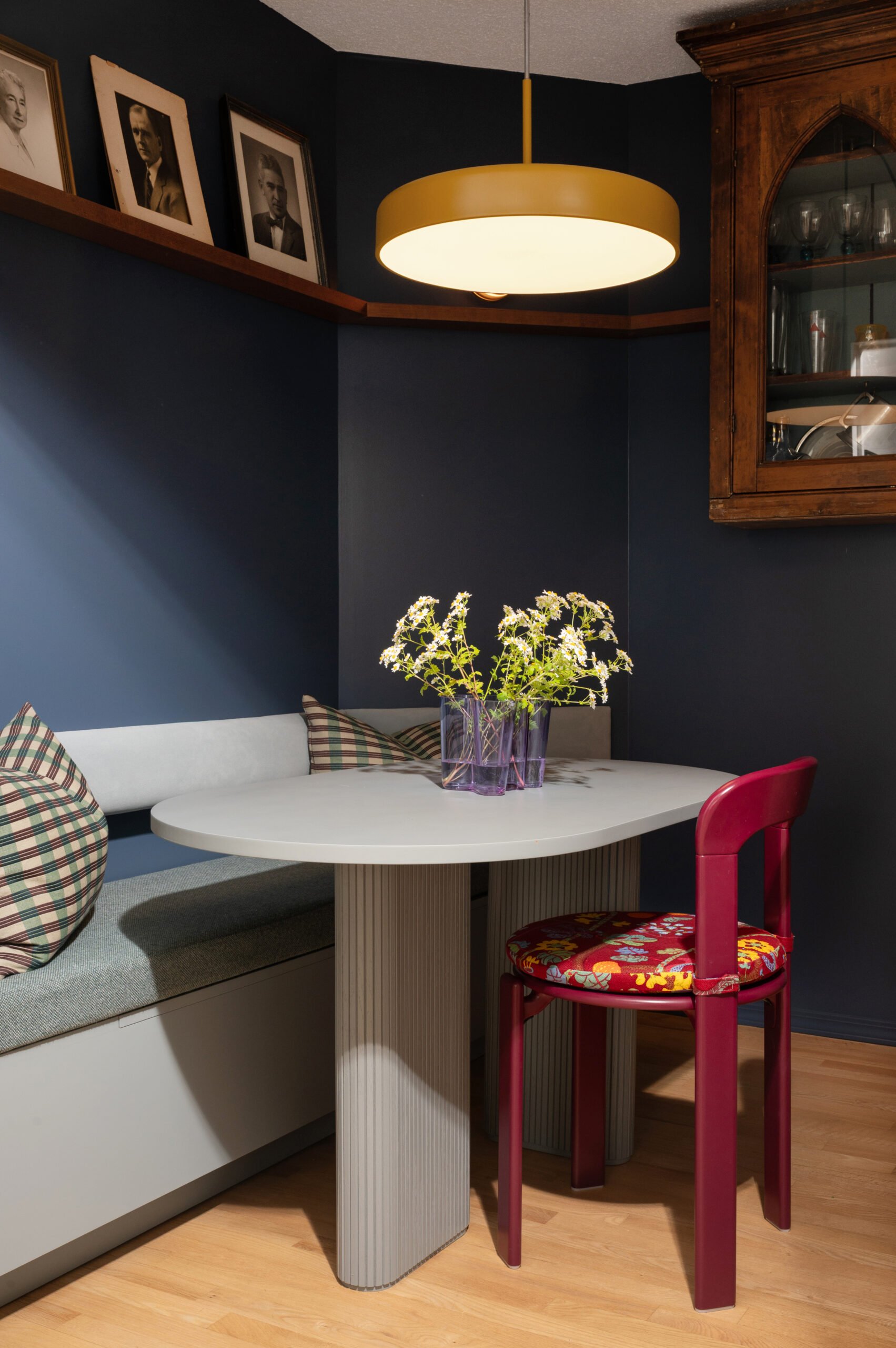 parlour with banquette seating, dining table, red chair, and antique hutch