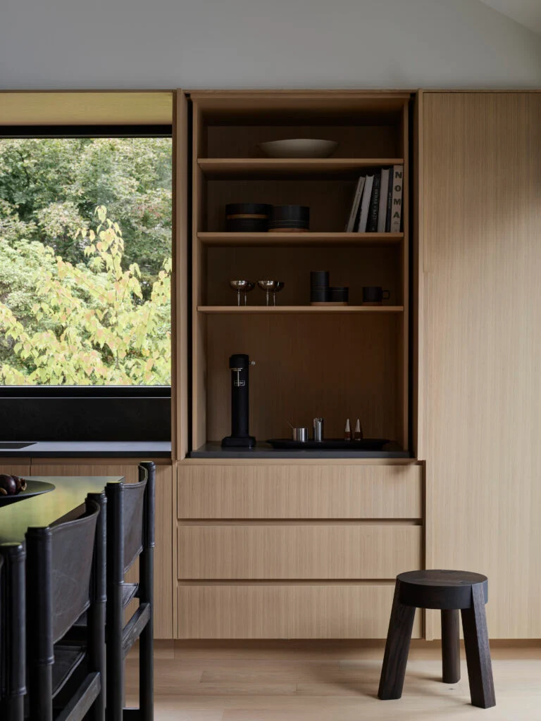 Custom wood kitchen millwork featuring drawers and a hidden mini bar with pocket doors that tuck away