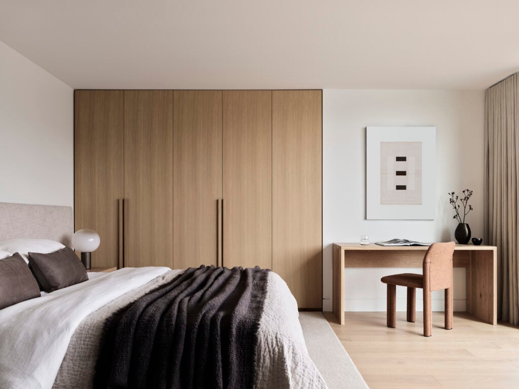 Bedroom featuring a built-in closet, warm neutral and wood tones and a small desk