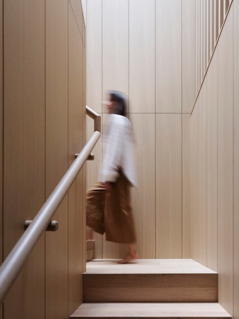 Woman walking up stairs with wood wall panelling