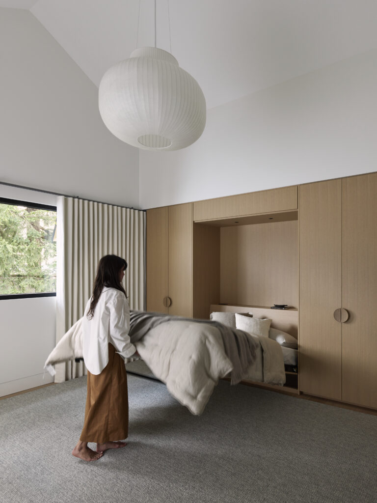A multi-purpose playroom and guest suite with built-in wood cabinetry, a Murphy bed and a white pendant light.