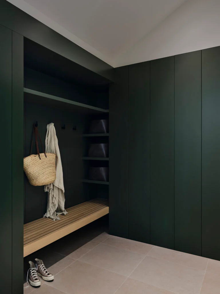 Dark green mudroom with built-in shelving and a wood bench