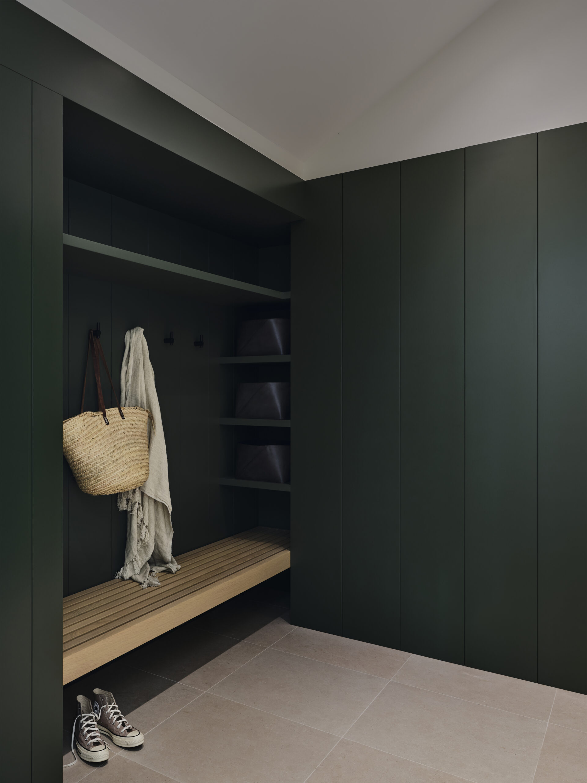 Dark green mudroom with built-in shelving and a wood bench