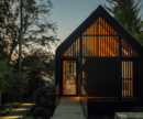 Cedar-clad studio with elevated walkway on a forested site