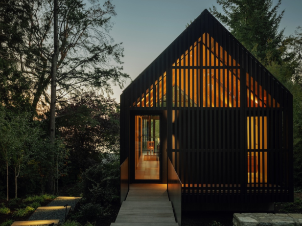 Cedar-clad studio with elevated walkway on a forested site