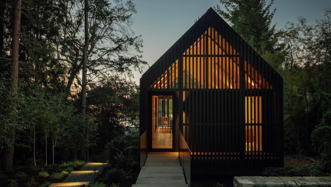 Cedar-clad studio with elevated walkway on a forested site