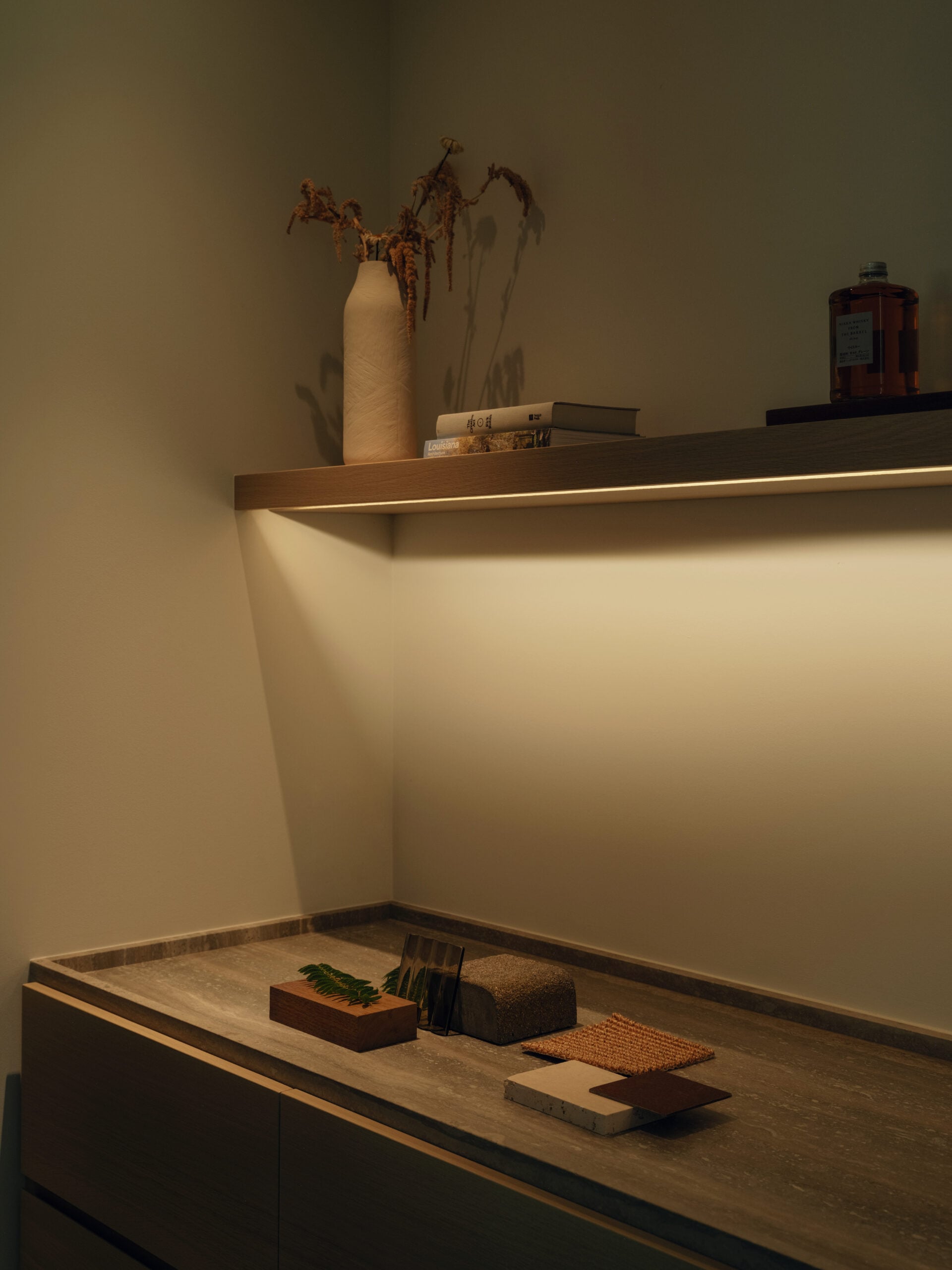 Small office with a built-in wood desk and illuminated open shelf