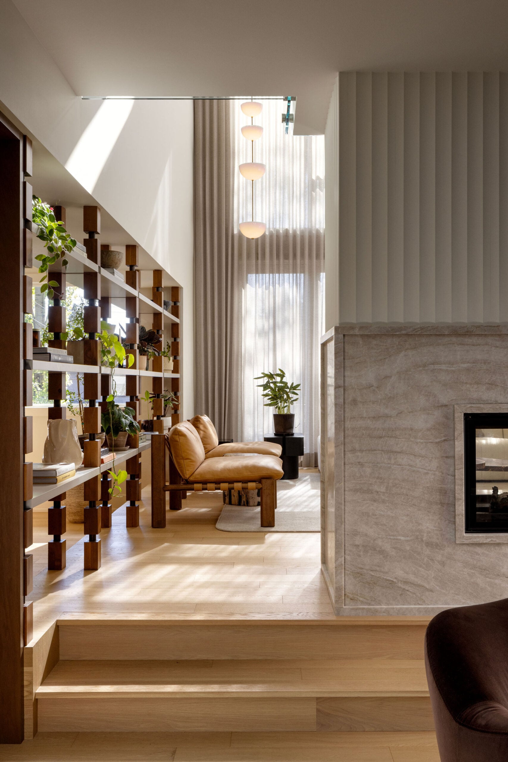 Double-height living room with large windows, hanging light and open shelving between kitchen and living room