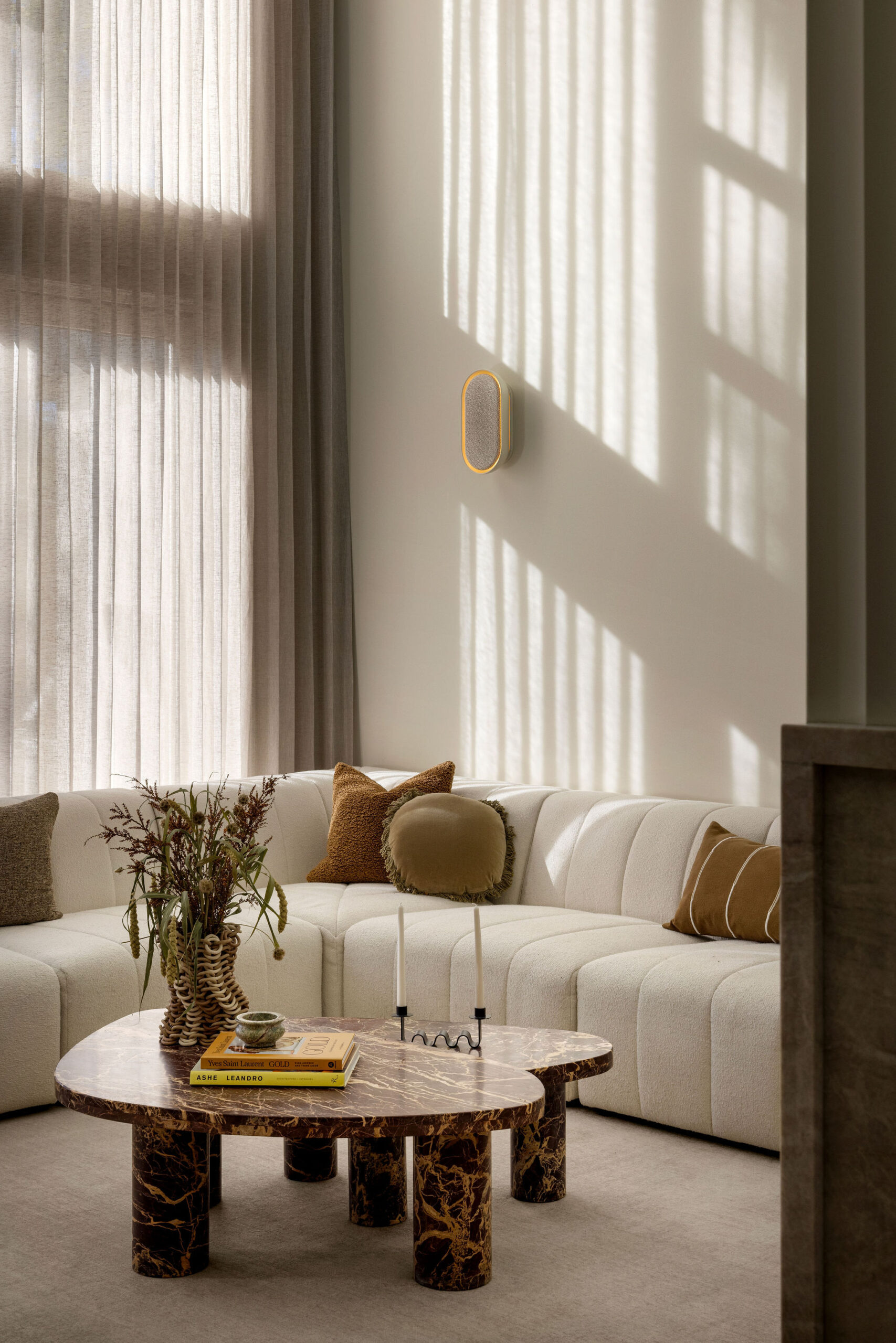 Double-height living room with cream sofa, marble coffee table, Mera Sound Sconce speaker and natural light