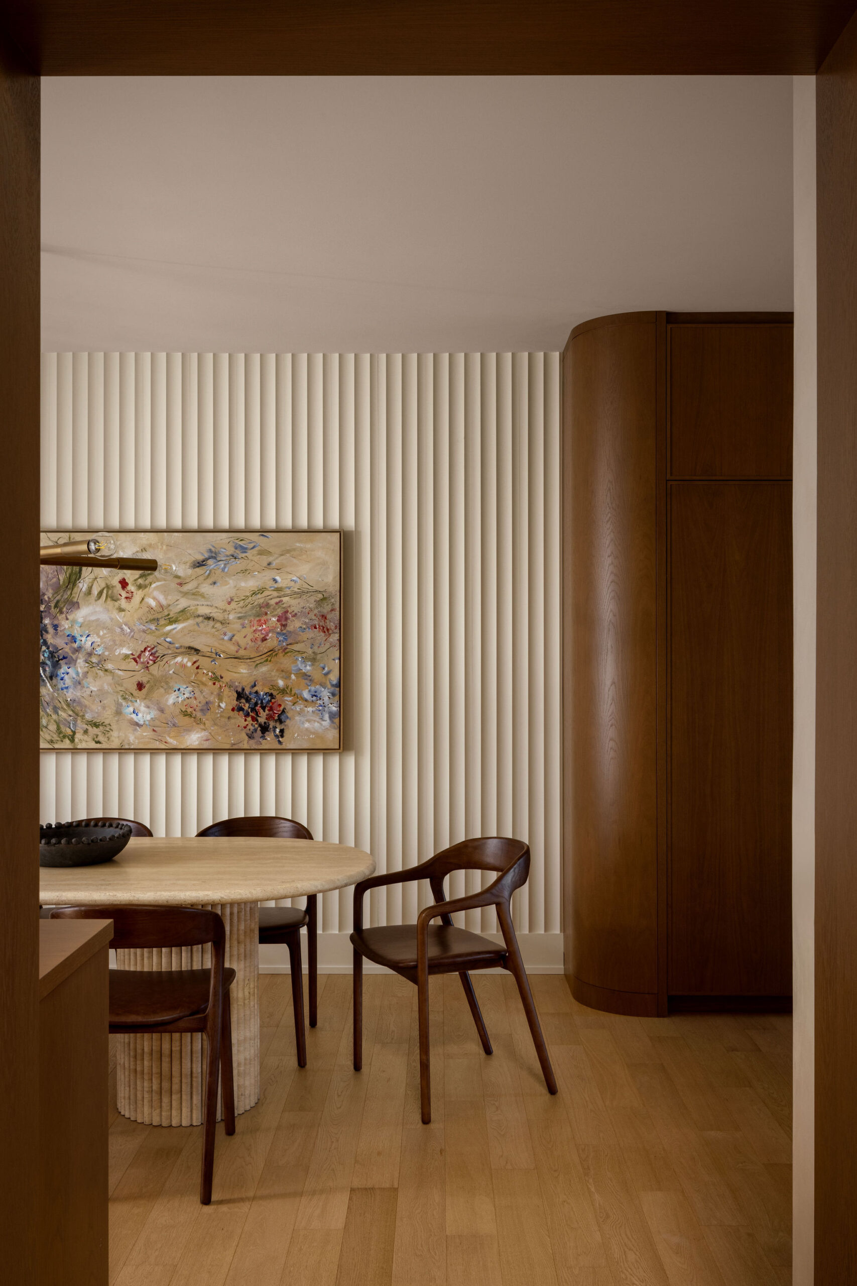 Dining area with cream fluted wall panels, marble dining table and wood chairs