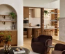 Lounge area with arched built-in shelving and bar, marble coffee table and dark brown armchairs