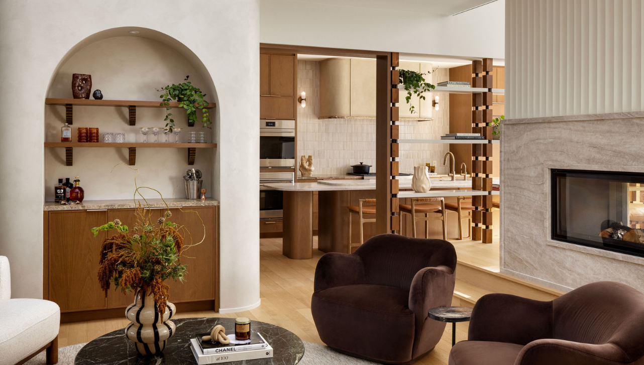 Lounge area with arched built-in shelving and bar, marble coffee table and dark brown armchairs