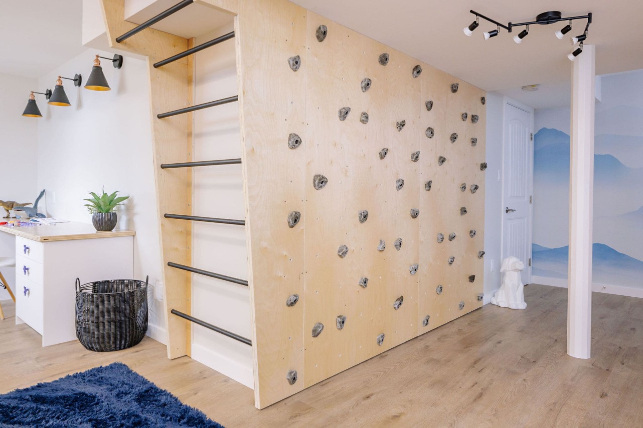 Monkey bars and a climbing wall inside of a basement bedroom.