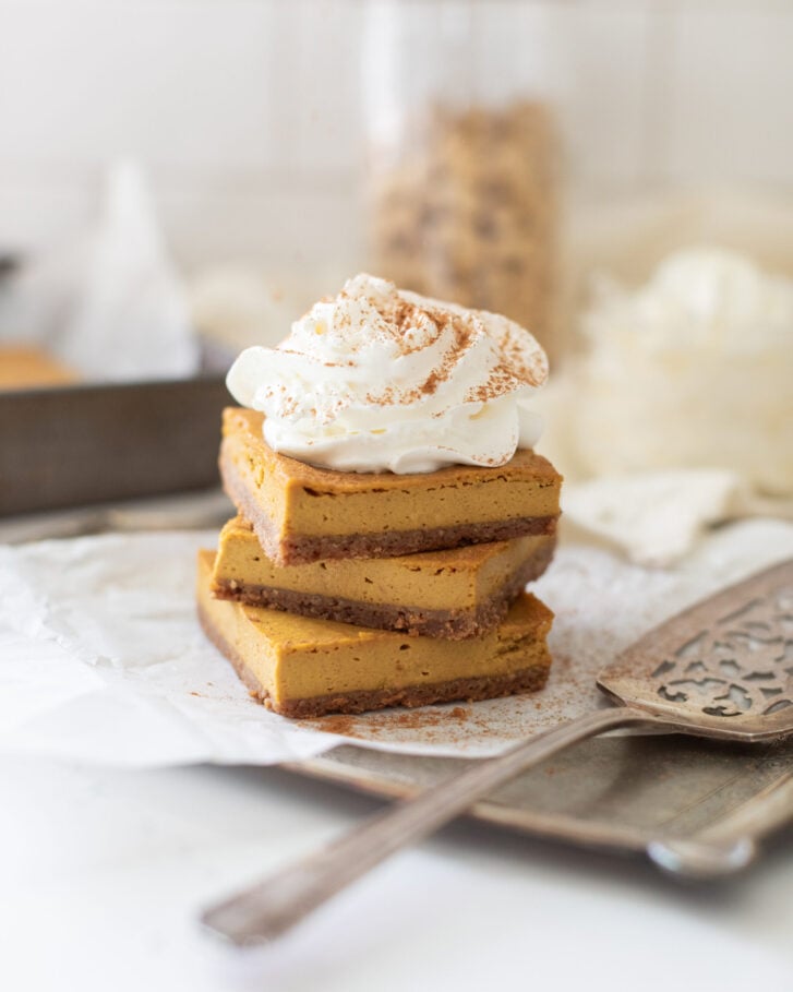 Pumpkin cheesecake bars by Tori Wesszer topped with Chantilly cream and cinnamon