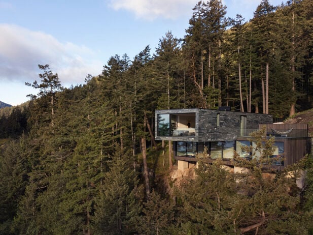 Modern cantilevered home on Bowen Island cliffside, surrounded by trees