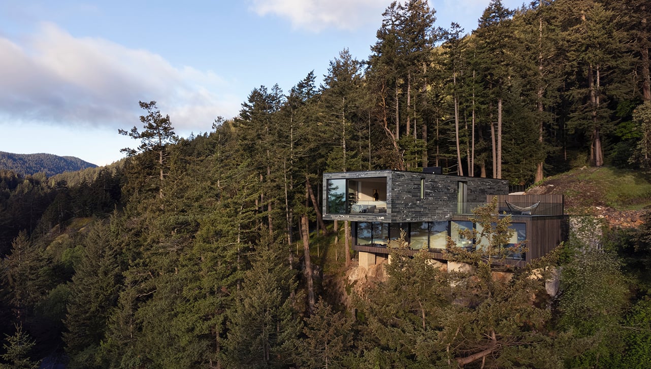 Modern cantilevered home on Bowen Island cliffside, surrounded by trees