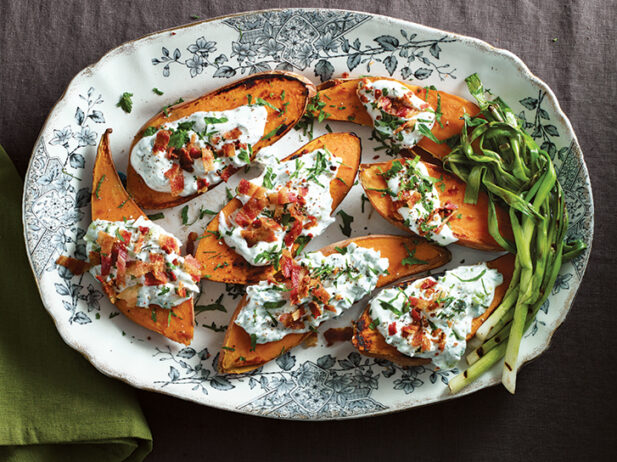 Close-up of roasted sweet potatoes showcasing golden edges, creamy scallion topping, crispy bacon and vibrant jalapeño.