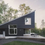 cabin with dark fibre cement siding, corrugated metal roof and outdoor terrace
