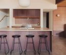 kitchen island with stools, pink tile backsplash and purple cabinetry