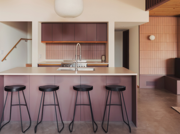 kitchen island with stools, pink tile backsplash and purple cabinetry