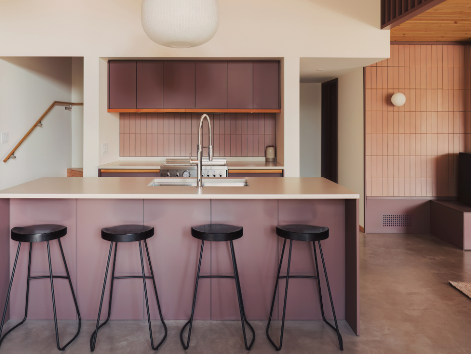 kitchen island with stools, pink tile backsplash and purple cabinetry