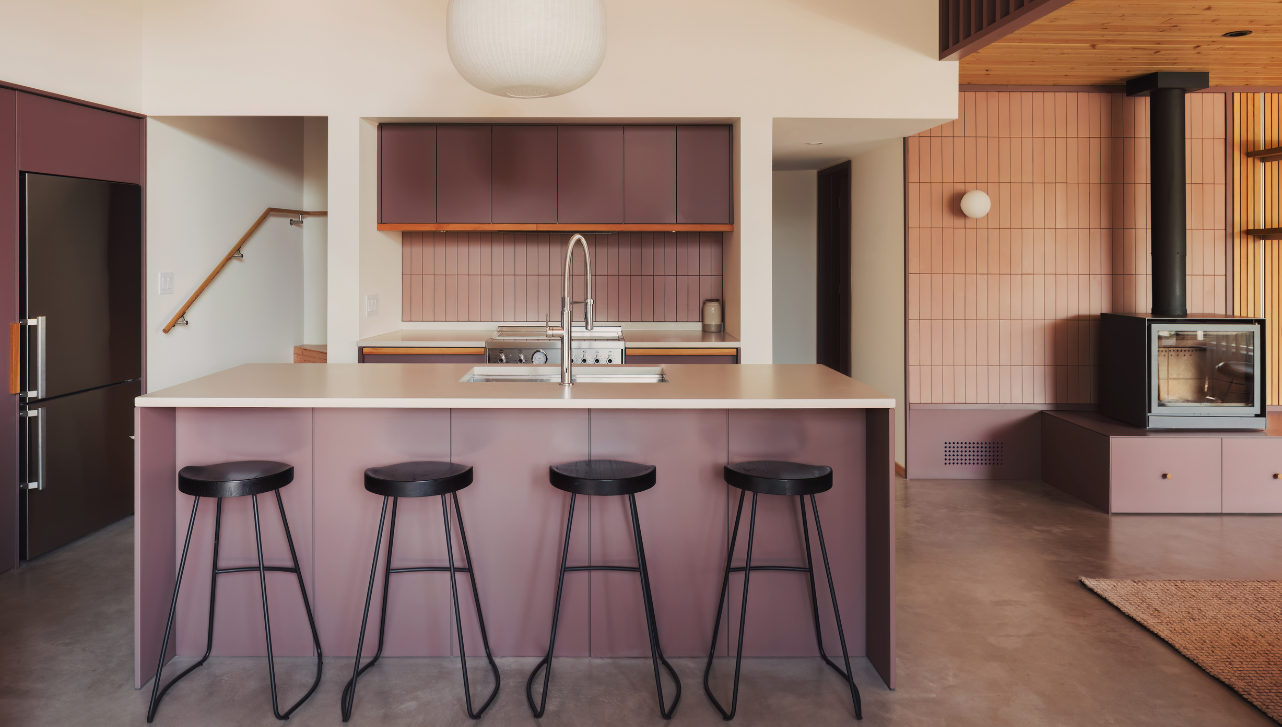 kitchen island with stools, pink tile backsplash and purple cabinetry