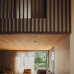 Living room with sofa, leather chairs, wood ceiling and upper floor railing