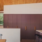 built-in purple cabinetry and kitchen island beneath wood ceiling