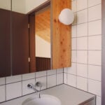 bathroom vanity with sink, mirror, sconce and white wall tiles