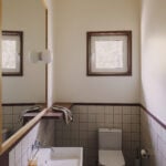 bathroom with wall-mounted sink, tiled walls with maroon grout and a large mirror